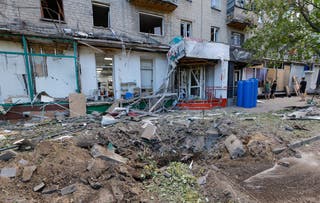 People cover broken windows in a damaged apartment building after the shelling
